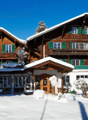 2 story brown wooden house, green windows, snow covered, balcony on the first floor