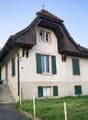 2 story house, green shutters, gable roof, wooden eaves, pathway, driveway