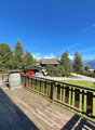 wooden deck, wooden railing, barrel, green grass, trees, mountains