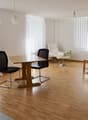 empty room, wooden floor, white walls, curtains, wooden table, two chairs, white armchair, green table, table lamp