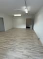empty room with wooden floor, two doors, and fluorescent ceiling lights