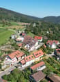 Cluster of houses in a village, each with unique architectural features, situated in a scenic rural area with a panoramic view of the mountains.