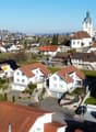 Aerial view of a neighborhood with several houses, one of which has a yellow circle highlighting a balcony