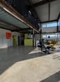 large open space, concrete floor, metal ceiling, large windows, modern furniture, artwork on wall