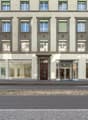 3 story building, multiple windows, glass doors, brown door, concrete sidewalk