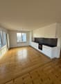 Empty kitchen with wooden floor, white cabinets, black countertops, white appliances, large windows