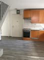 empty kitchen with wooden cabinets, tiled floor, white walls, staircase