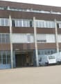 large office building, brown color, many windows, large entrance, trucks and cars parked in front