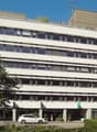 modern office building, white exterior, large windows, ground floor commercial space, surrounding greenery