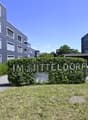 Entrance to a residential building complex with a sign reading 'IM MITTELDORF', surrounded by greenery and a pathway.