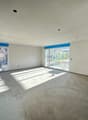Empty room, white walls, gray floor, two large windows, bright daylight