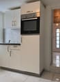 modern kitchen with white cabinets, black countertop, built-in oven, sink, and faucet, white tiled floor, window with view