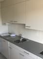 Modern kitchen with white cabinets, gray countertops, stainless steel sink, and a built-in dishwasher