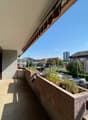 elevated balcony with large planter, railings, cars parked in lot below