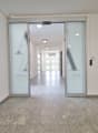 Empty hallway with gray tiles, glass doors, and ceiling lights