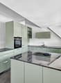 modern kitchen with green cabinets, granite countertops, built-in oven, sink, and faucet, large windows