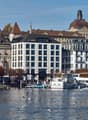 Urban waterfront with buildings, Credit Suisse logo, water, docked boats, people, flags