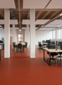 modern office space with desks, chairs, monitors, cabinets, radiators, plants, red floor, white walls, large windows