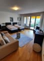 Two twin beds, couch, side tables, TV, lamps, rug, large windows, balcony with chairs