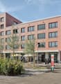 Multi-story brick building with large windows, balconies, and ground-floor commercial spaces including a lounge bar and cafe.