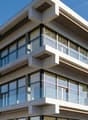 modern design, concrete structure, multiple floors, large glass windows, balconies