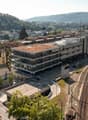 Building with multiple stories, green roof, glass windows, parking lot, train tracks