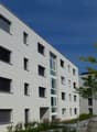 Modern apartment building, white exterior, multiple windows, parking sign