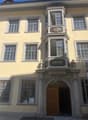 yellow building, multiple windows, wooden door, balcony with intricate design, decorative elements