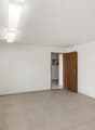 Empty room with white walls, tiled floor, large window, open door leading to another room