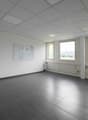 empty room, white walls, gray tiles, three windows, open door, radiators, bulletin board