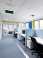 modern office space, blue flooring, blue and white partitions, desks, black office chairs, monitor and telephones
