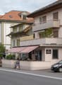 Building with a red awning, balcony, and a car parked in front