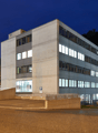 modern office building, white exterior, multiple floors, parking lot in front