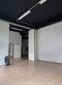 Empty room, black ceiling, white walls, tiled floor, open doors, metal ladder, trash bin