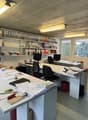 desks, black office chairs, bookshelves, computer, papers, potted plant, picture frame, storage boxes, bicycles