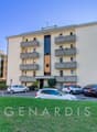 4 story building, beige exterior, multiple balconies, parking lot, multiple cars parked