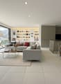 open living area with sofa, coffee table, wooden dining table, large windows with terrace, kitchen, shelving unit, chandelier, zebra painting