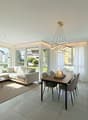 Modern design living room with dining area, white couch, large windows, wooden dining table, modern pendant light, rug, table lamp