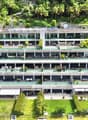 Multi-story apartment building with balconies, surrounded by lush greenery and trees