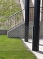 small fenced yard with short manicured lawn, stone retaining wall, black balustrade with metal railings