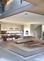 Open-concept living space with large windows, modern kitchen, dining area, and living room. Sliding glass doors lead to an outdoor terrace or balcony area.