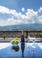 Table with view of mountains and city, bottle of champagne and two wine glasses