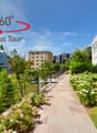 Pathway, fence, flowering plants, bushes, lawn, buildings, mountain range