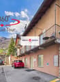 Building with stone walls, balcony with railings, parked cars, and a sign indicating a virtual tour.