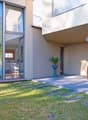 modern house, large glass windows, outdoor dining area, potted plant, grassy lawn