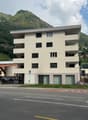 4 story building, white exterior, multiple windows, parking area in front