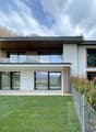 Modern house, white exterior, large glass windows, balcony, wooden fence, well-maintained lawn