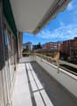 large balcony with tiled floor, metal railings, retractable awning, view of mountains