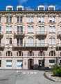Large building with arched windows, decorative balconies, arched entryway, multiple floors, pink exterior, arched doors, central courtyard area