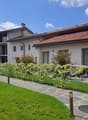 2 story building, brick roof, solar panels, balconies, windows, walkway, grass, fence, plants